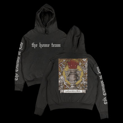 front and back of  black hoodie. the front says "the home team" across the chest in white block letters. the back has a rectangular print that features white, red, gold and black abstract shapes. below this is a white banner and in black text reads "the crucible of life". the right hoodie sleeve also says this in white block text.
